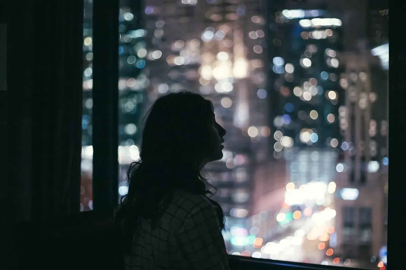 A young woman looking out over the city lights at night